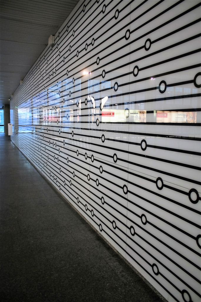 Szklany panel na ścianie starej antresoli. Identyczne panele zastosowane zostały w zmodernizowanym w 2015 r. korytarzu  zachodnim pod Al. Jana Pawła II. Fot. Jerzy S. Majewski